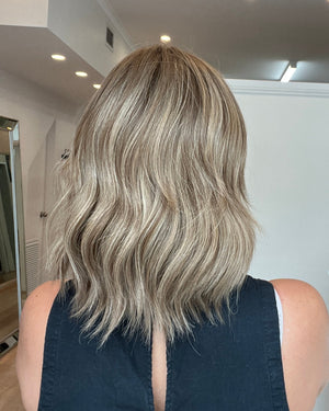 Person with wavy, shoulder-length hair in a salon setting