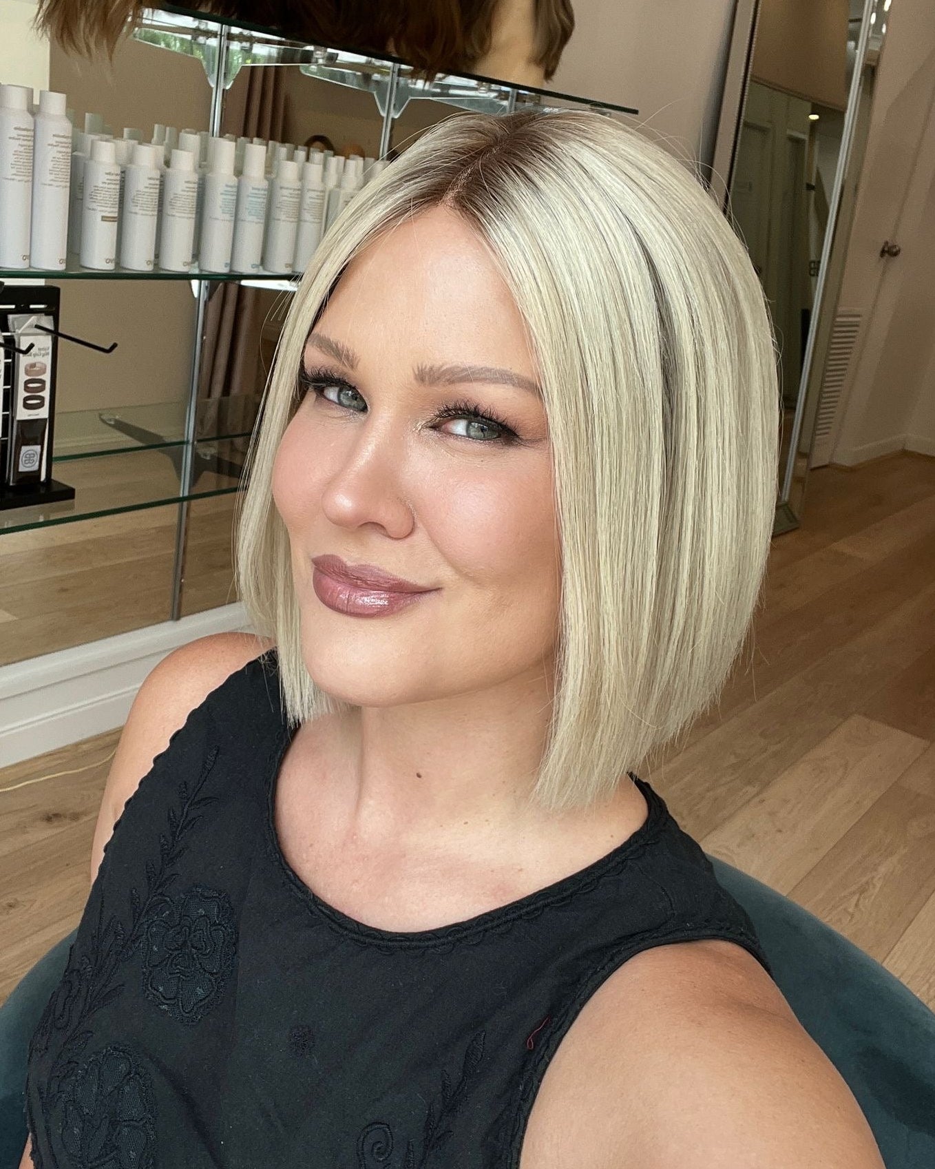 A woman showcasing a 12-inch platinum blonde bob wig with a lace front and a silicone grip cap.