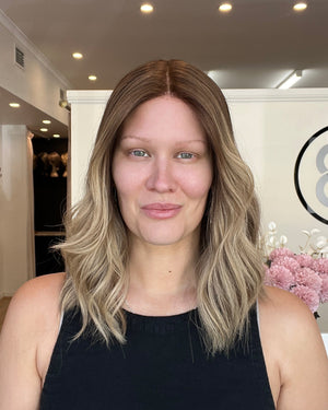 Woman with shoulder-length hair standing indoors in a well-lit room.