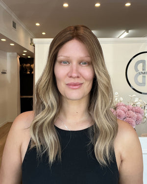 Woman with long blonde hair in a black top standing in an indoor setting.