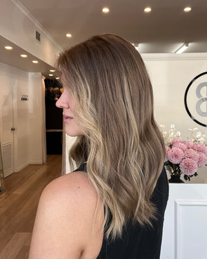 Woman with styled hair in a salon setting with decor elements.