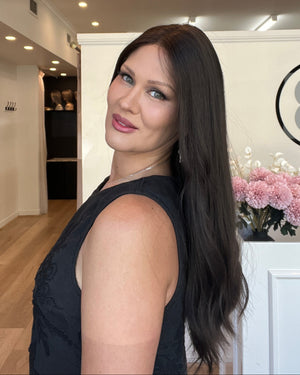 Woman in a black dress standing indoors with a blurred background
