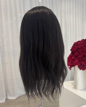 Black topper on a mannequin head with a white curtain and red flowers in the background