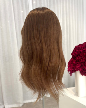 Brown topper on a mannequin head with a white curtain background