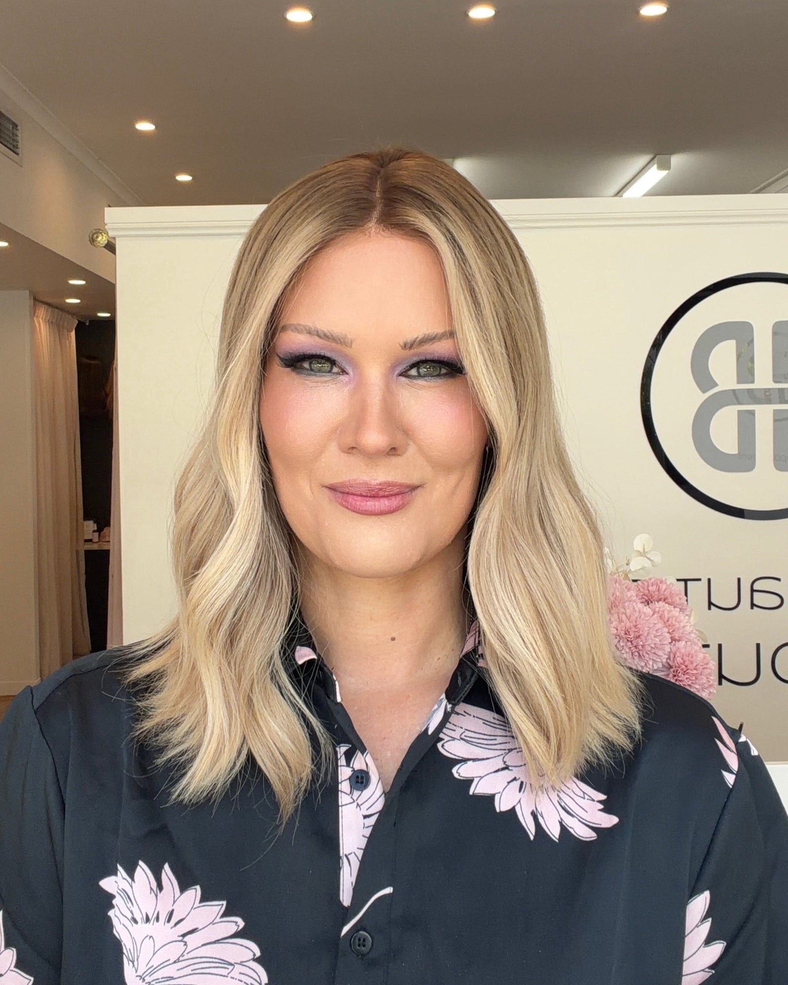 Woman with blonde hair and floral patterned shirt in an indoor setting