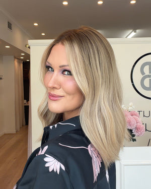 Woman with blonde hair in a room with a visible brand logo on the wall.