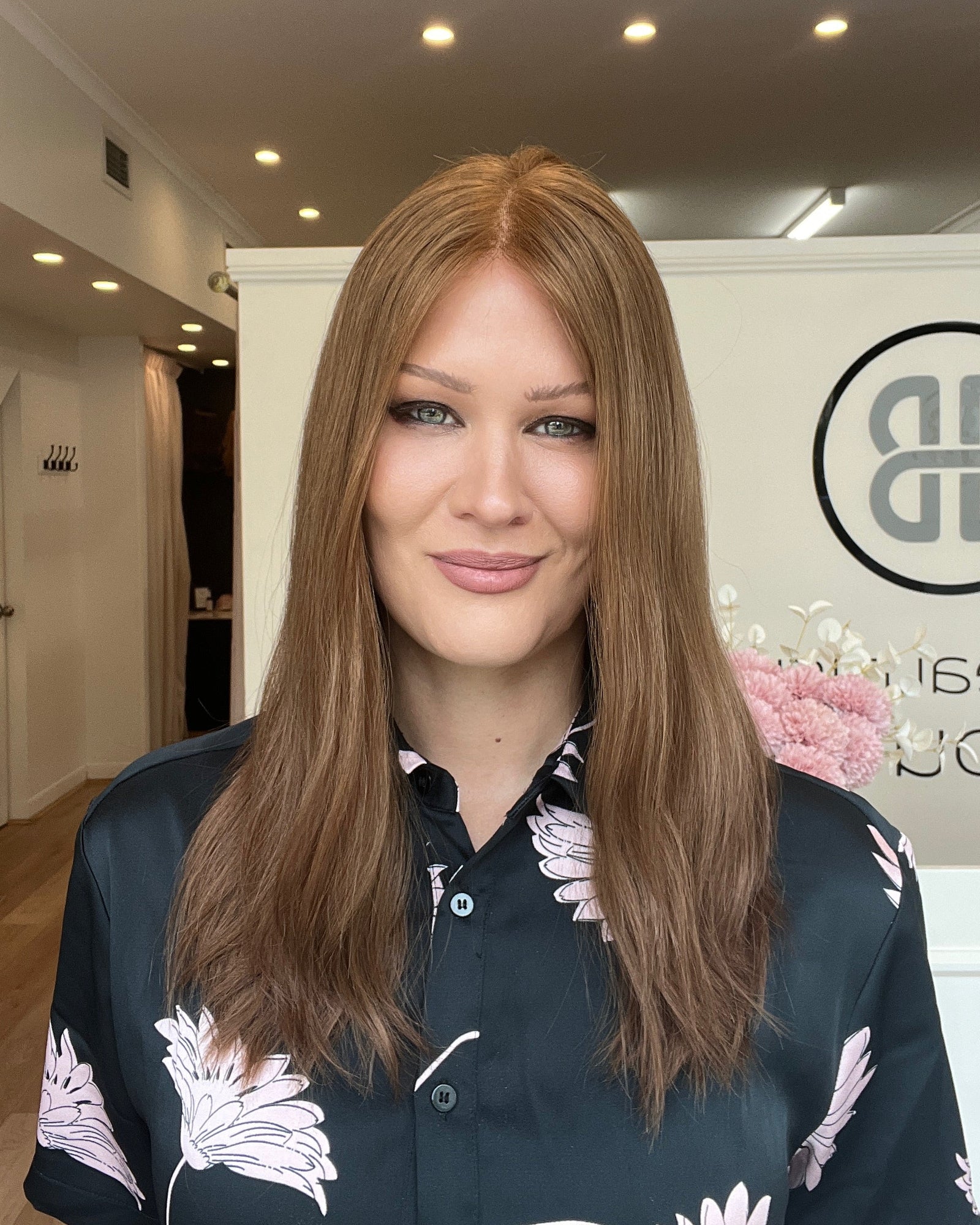 Woman with long reddish brown hair in a room with a logo on the wall