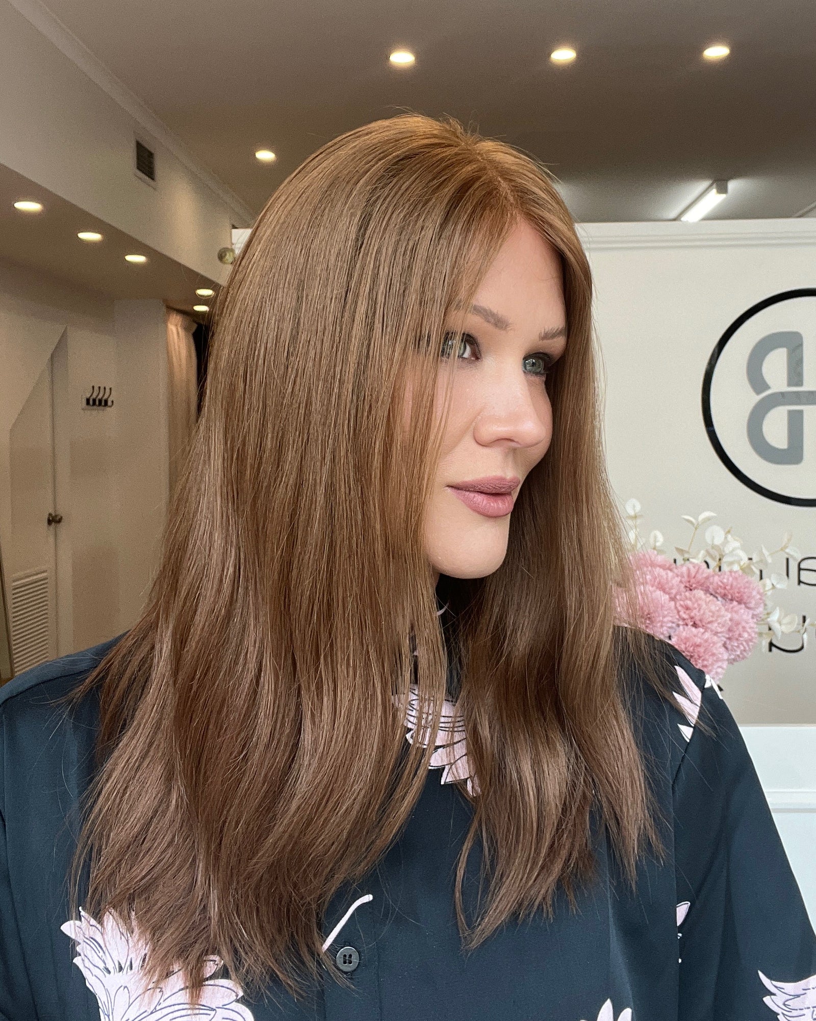Woman with long reddish brown hair in a room with a logo on the wall