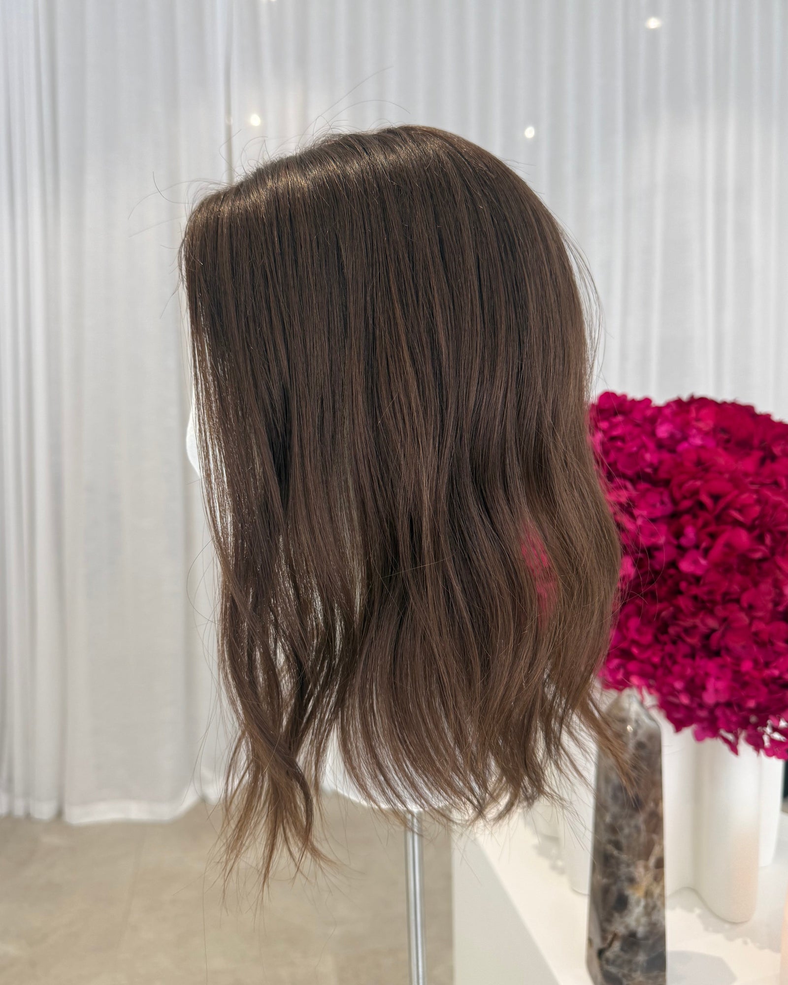 Brown hair extensions on a cmannequin head with a blurred background