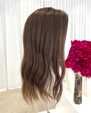 Brown topper on a mannequin head with a white background and pink flowers.